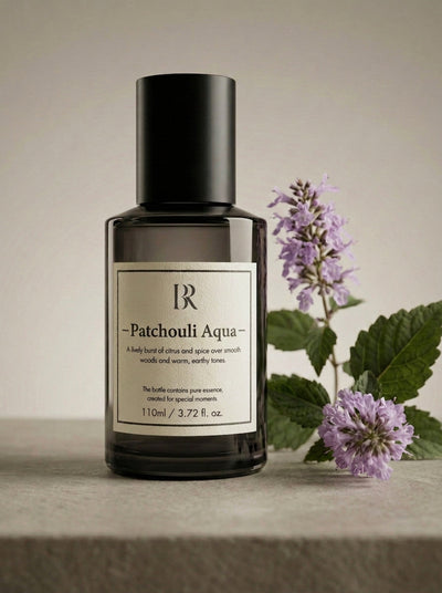 Esență de parfum ambiental Barrano Patchouli Aqua 110ml — flacon pe fundal neutru cu flori de mentă